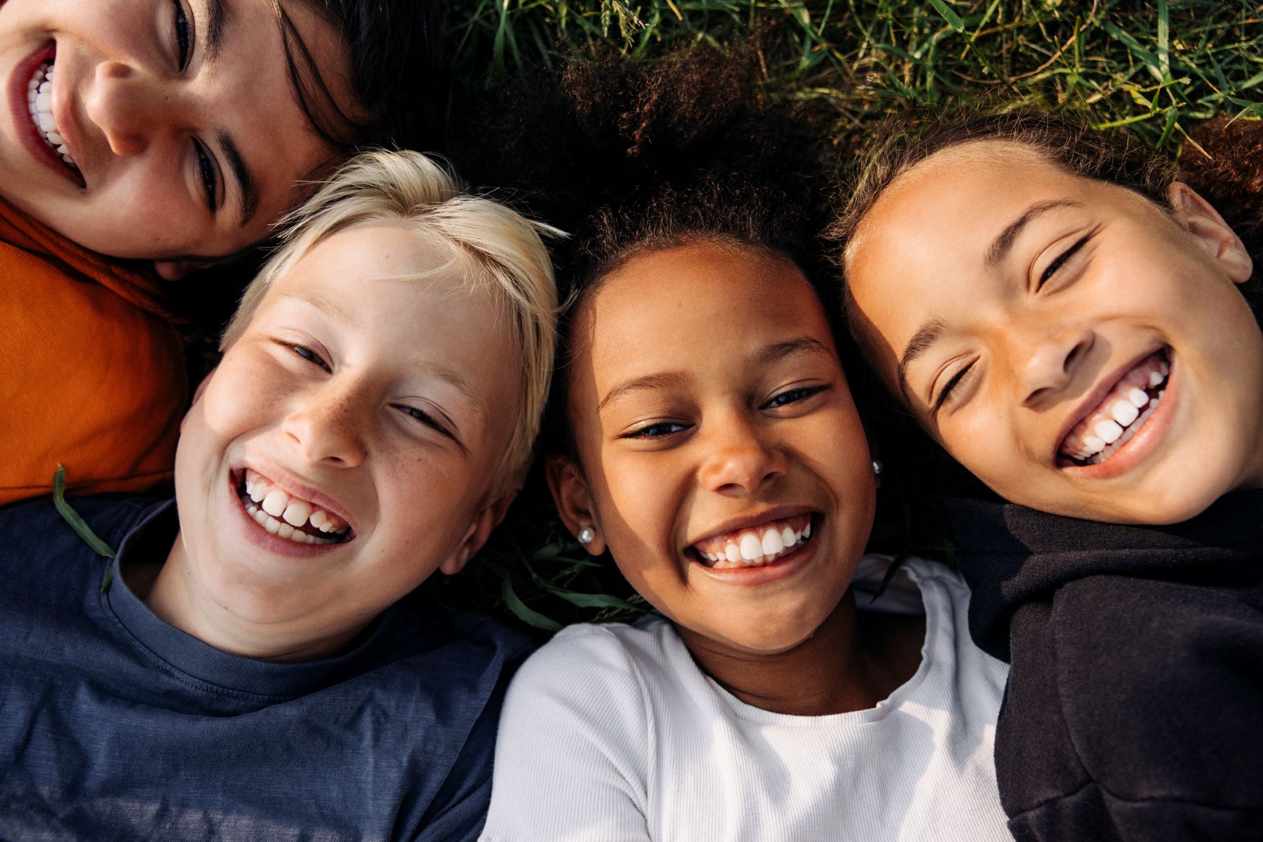 group of smiling kids lying in the grass