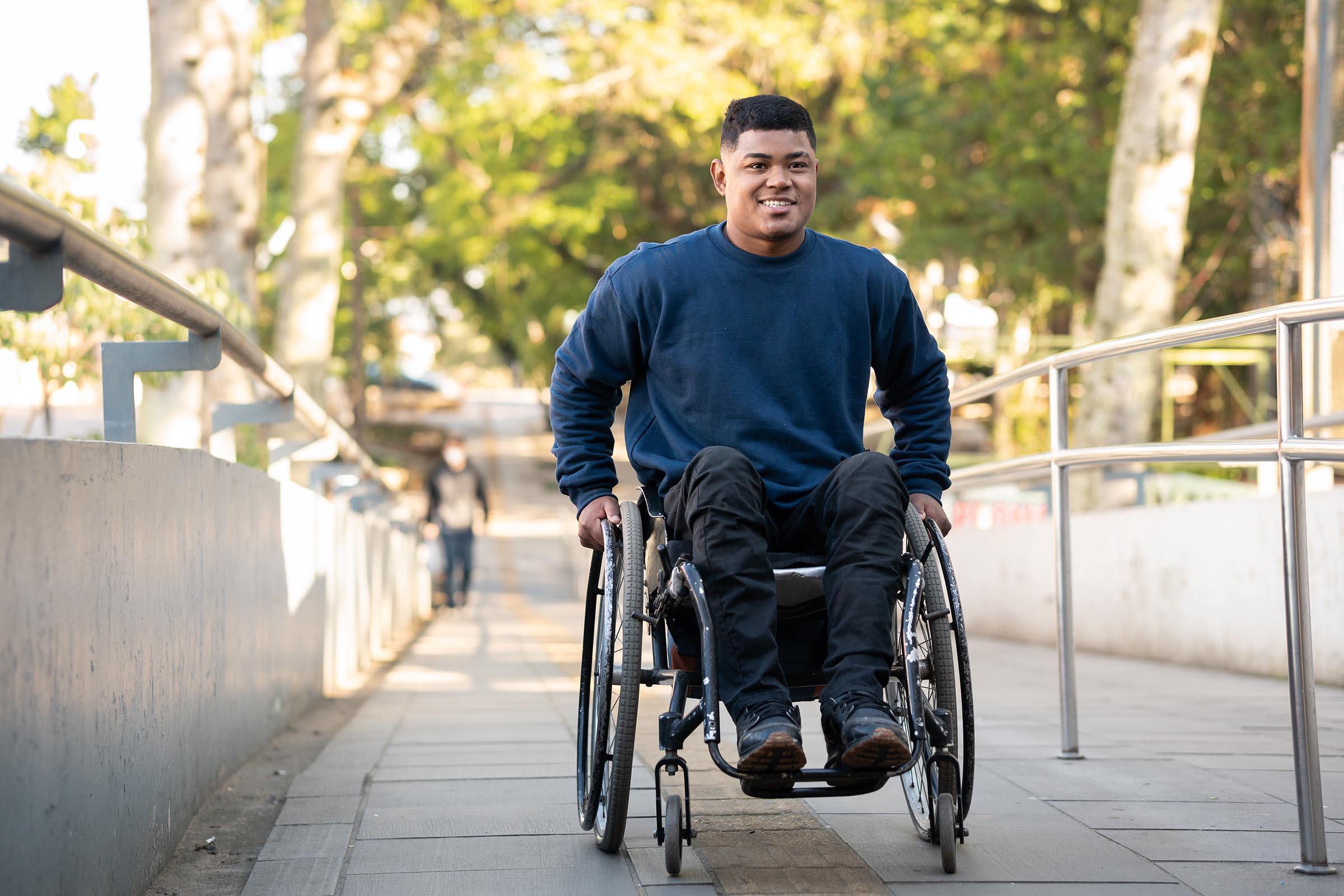 Smiling young man in wheelchair going up a ramp