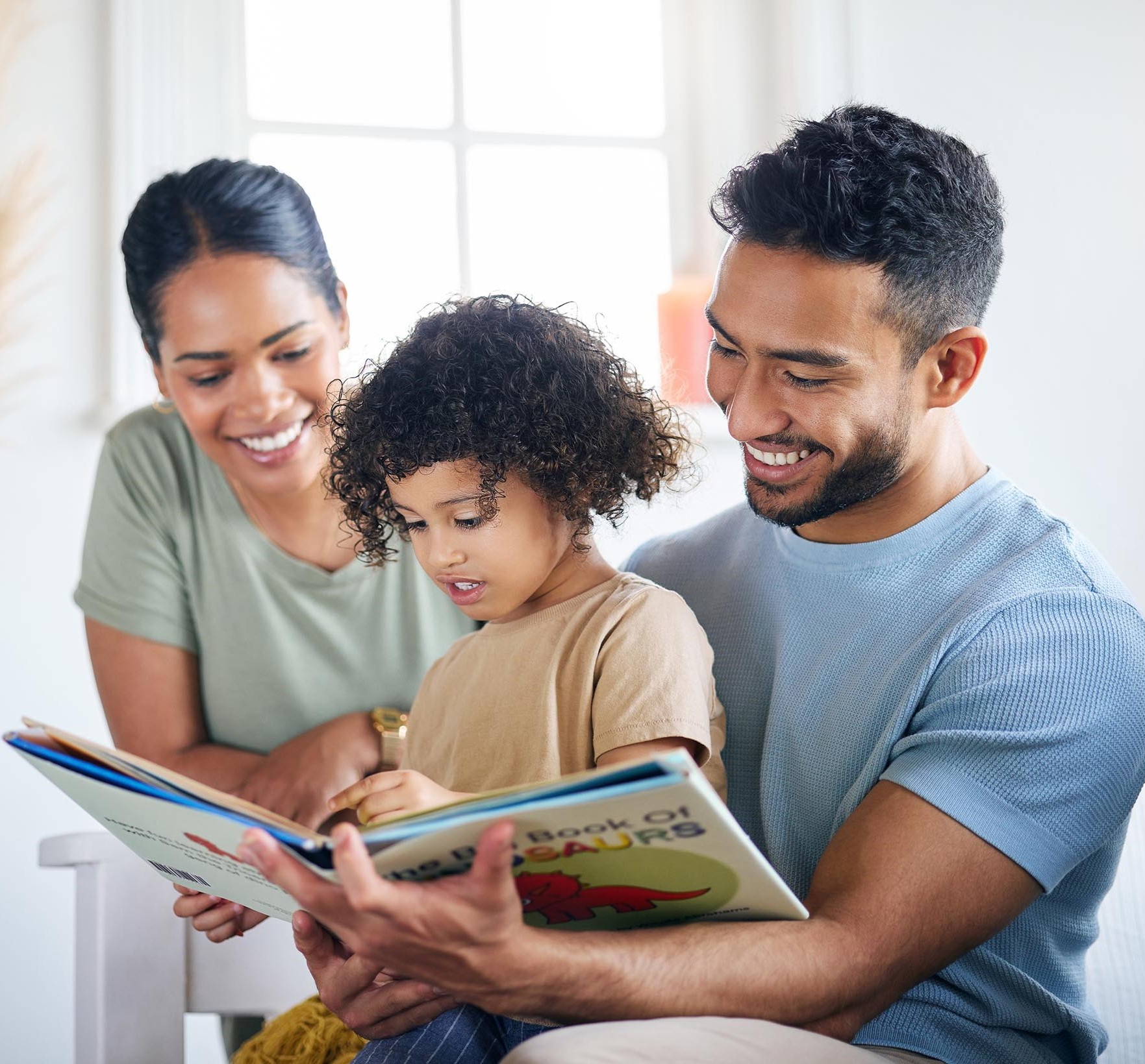 Young family smiling and reading a book together