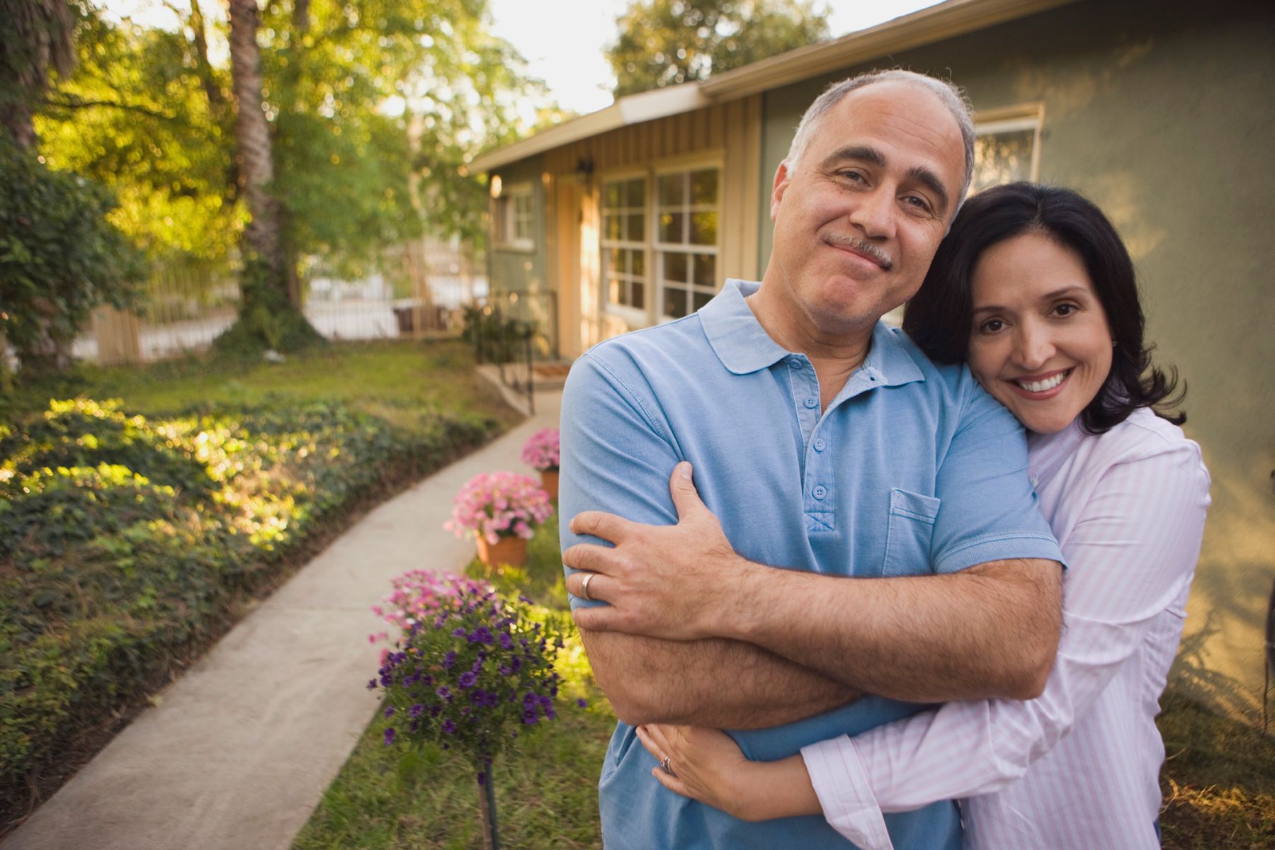 woman with arms around her husband standing smiling at the camera