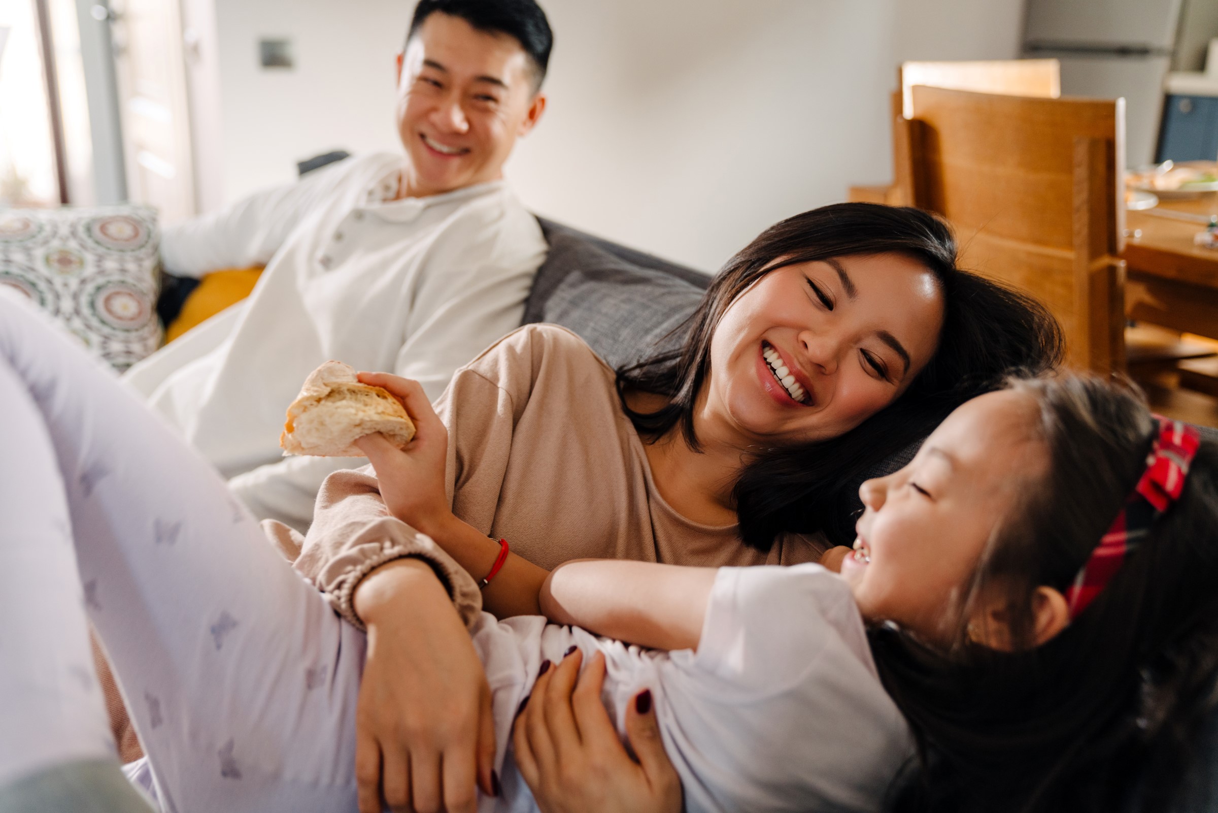 Couple with their young daughter cuddling on the couch