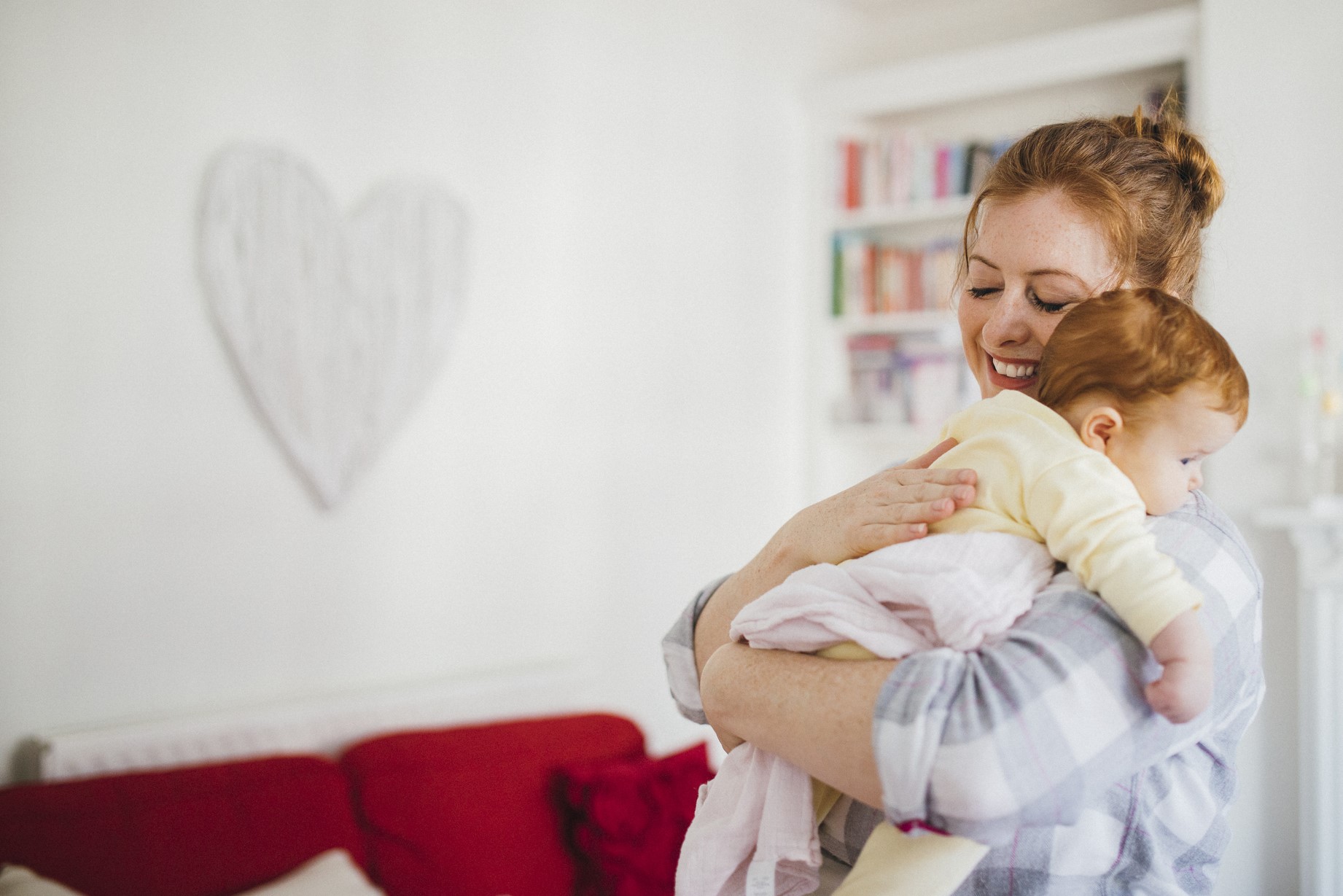 Smiling young mom holding her baby at home