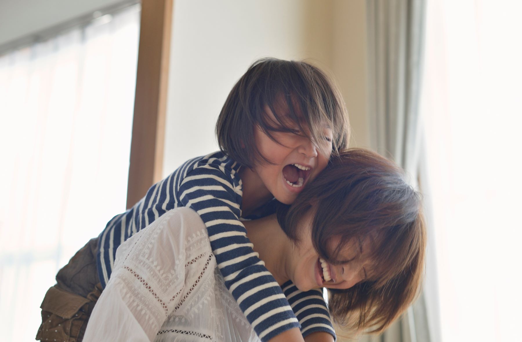 Laughing mom with young daughter riding piggyback